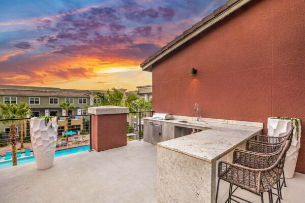 Rooftop patio with stone bar, built in BBQ grill, sink, and railing.