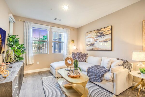 Living room with plush couch, console with decor, framed art, and large window.