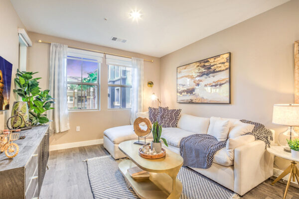 Living room with plush couch, console with decor, framed art, and large window.