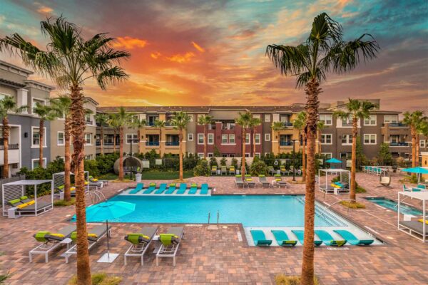 Pool area with lounge chairs, gazebos, and tall palm trees.
