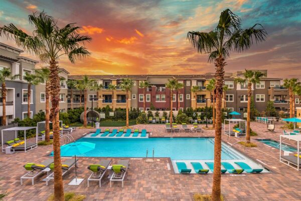 Pool area with lounge chairs, gazebos, and tall palm trees.