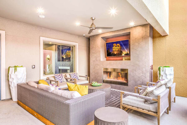 Indoor/outdoor lounge with plush seating, ceiling fan, and TV.