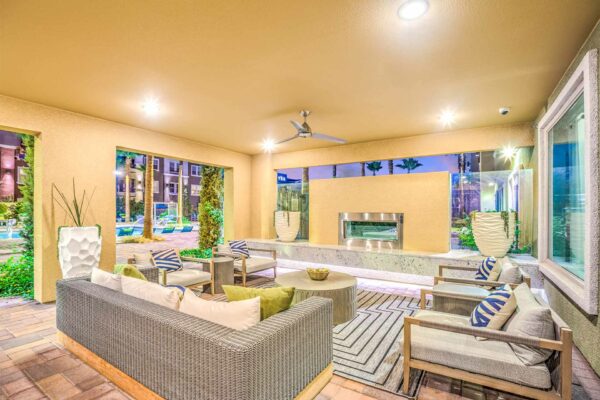 Lounge with plush furniture, ceiling fan, fireplace, and large windows.