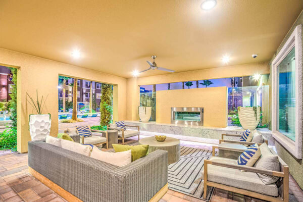 Lounge with plush furniture, ceiling fan, fireplace, and large windows.