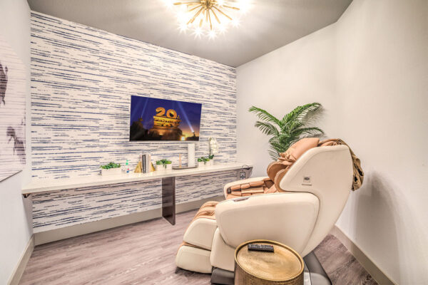 Spa room with massage chair, large plants, and TV.