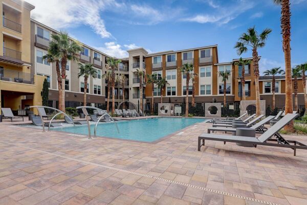 Aspire at Echelon apartments pool area with lounge chairs, daybeds, and tall palm trees.