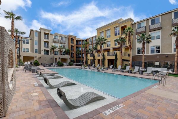 Aspire at Echelon apartments pool area with lounge chairs and tall palm trees.