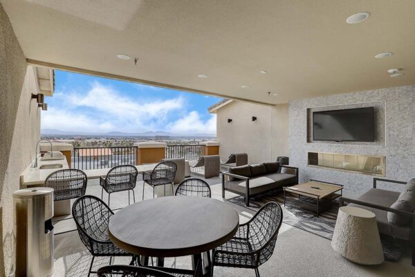 Aspire at Echelon apartments rooftop lounge with plush seating, dining table, TV, and fireplace.
