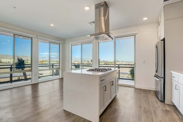 Aspire at Redwood apartment kitchen with wood style floor, white cabinets, light counters, and stainless steel appliances.