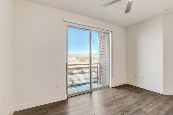 Aspire at Redwood apartment bedroom with wood style floor, ceiling fan, and balcony door.