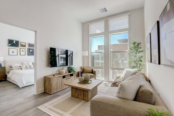 Aspire at Redwood apartment living room with plush couch, wall mounted TV, and large windows.
