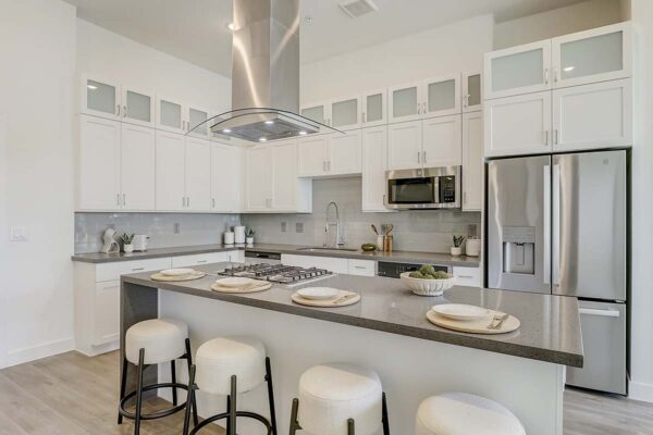 Aspire at Redwood apartment kitchen with wood style floor, white cabinets, gray counters, and stainless steel appliances.