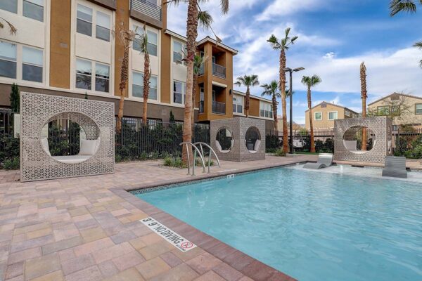 Aspire at Echelon apartments pool area with lounge chairs, daybeds, and tall palm trees.