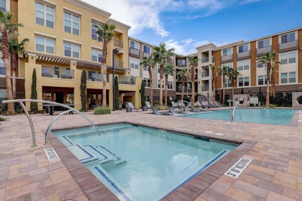 Aspire at Echelon apartments pool area with spa, lounge chairs, daybeds, and palm trees.