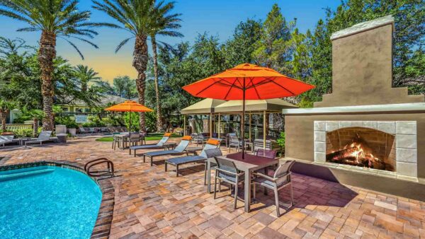 Pool area with lounge chairs, gazebos, and outdoor fireplace.