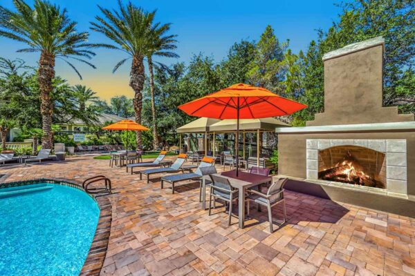 Pool area with lounge chairs, gazebos, and outdoor fireplace.