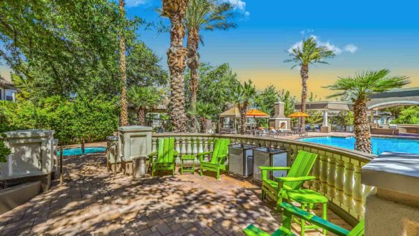 Adiamo lounge area with lounge chairs and palm trees overlooking pool.