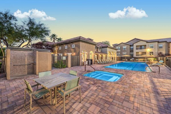 Pool area with dining table, spa, and pool with lounge chairs.