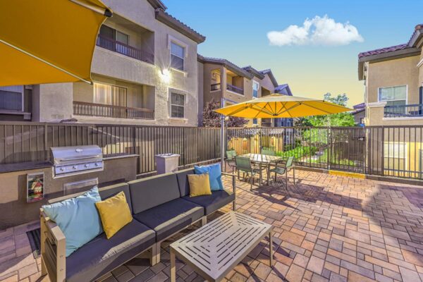 Outdoor lounge with plush seating, dining table, and built in BBQ grill.