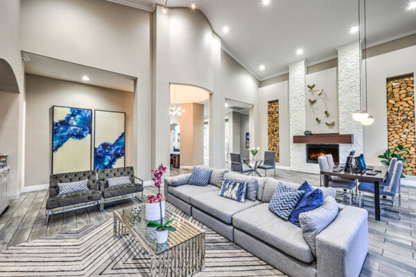Lounge with plush seating, large framed artwork, desks with computers, and fireplace.