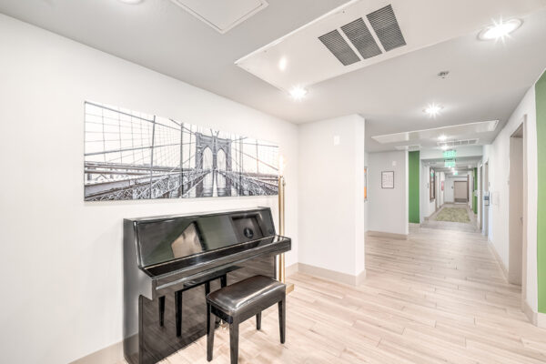 Hallway with wood tile floors, large artwork, lamp with Edison bulb, and piano.