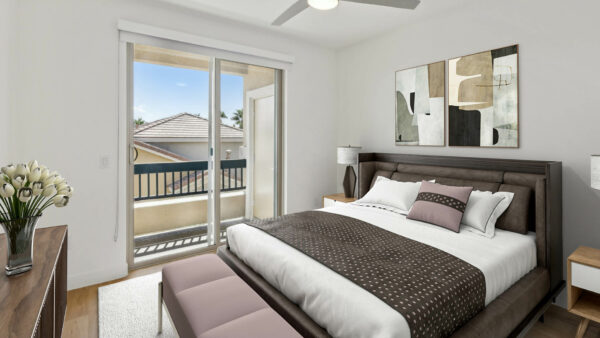 bedroom in Henderson apartment with large wood bed, bedside tables with lamps, and balcony door.