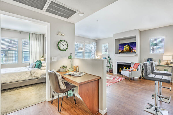 Living area with built in desk, comfortable living room, and door to bedroom.