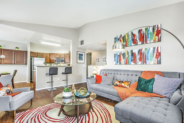 Living room with plush couch, large lamp, coffee table with decor, and colorful artwork.