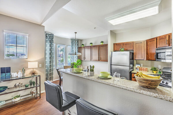 Kitchen with wood cabinets, stone counters, stainless steel appliances, and breakfast bar with stools.