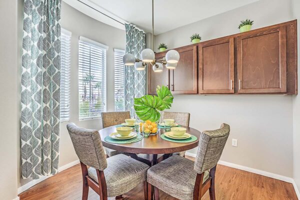 Dining room with wood dining table, plush chairs, wood cabinets, and large windows.