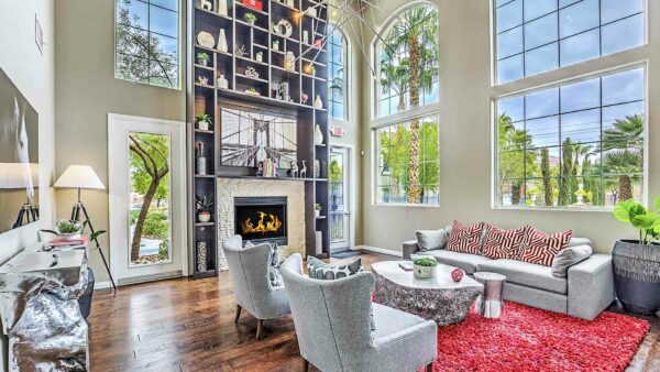 Clubhouse with plush seating, shelves with decor, fireplace, and two story windows.