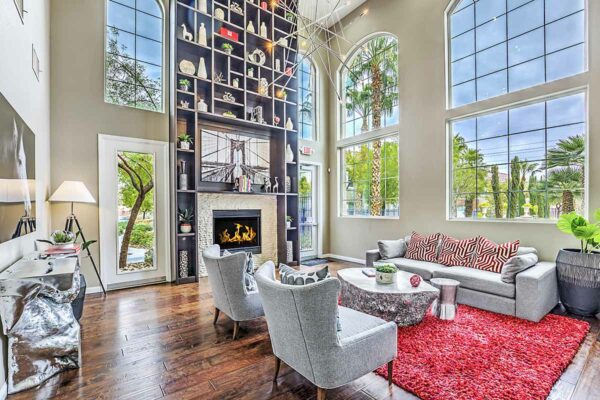 Clubhouse with plush seating, shelves with decor, fireplace, and two story windows.
