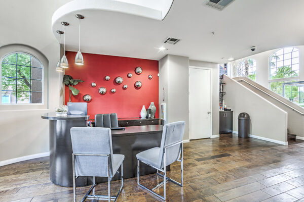 Leasing center with tile floors, leasing desk with chairs, and red accent wall with artwork.