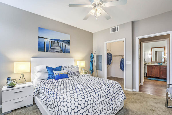 Bedroom with plush bed, bedside drawers with lamps, large artwork, and doors to closet and hallway.