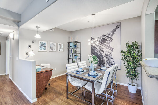 Dining area with built in computer desk, dining table with sleek chairs, shelves with decor, and large artwork.