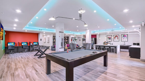 Lounge with pool table, computer desks, demo kitchen, poker table, and framed art.