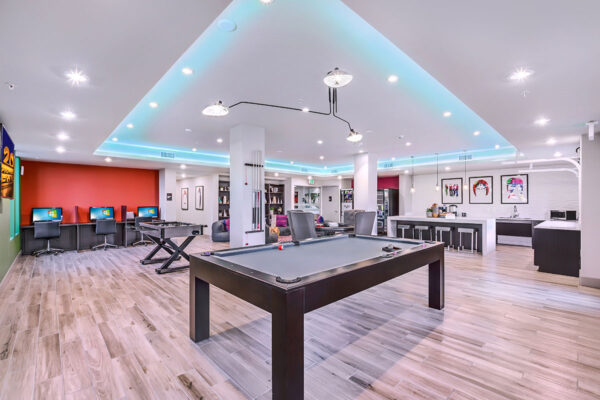 Lounge with pool table, computer desks, demo kitchen, poker table, and framed art.