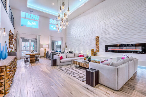 Clubroom with plush seating, large fireplace, chandelier, and tall ceilings.