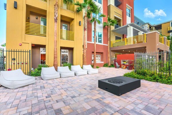 Outdoor lounge with plush seating, fire pit, stone paver patio, and lush landscaping.