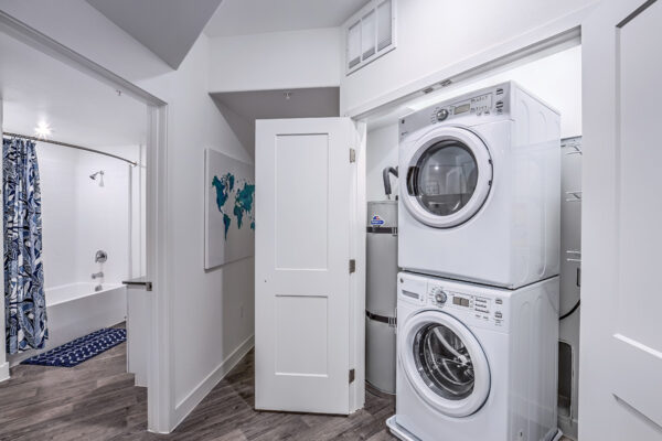 Laundry closet with stacked washer dryer, water heater, and wire shelves.
