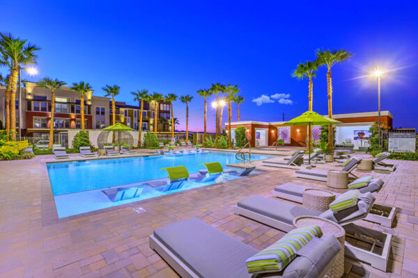 Pool area with lounge chairs, umbrellas, gazebo, and tall palm trees.