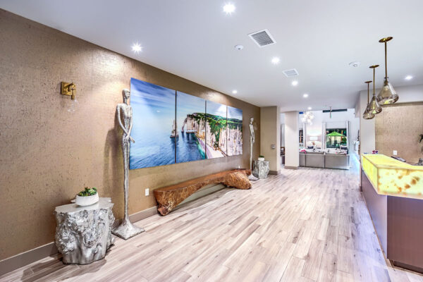 Entrance hall with tall sculptures, wood bench, and large artwork.