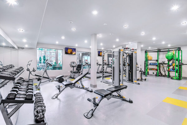 Fitness center with cardio machines, weight lifting equipment, large windows, and TV.