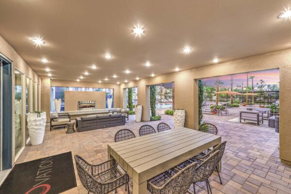 Outdoor lounge with large tables, potted plants, and large fireplace.