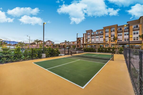 Pickleball court with tall lamps and metal fence.