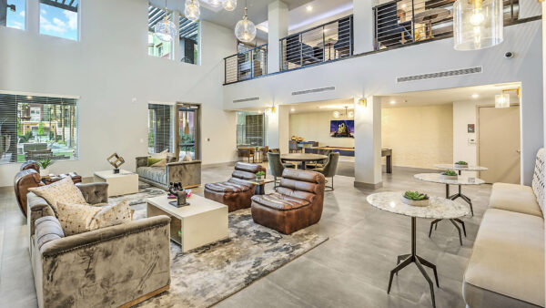 Clubroom with plush seating, tables with decor, glass light fixtures, and mezzanine floor.