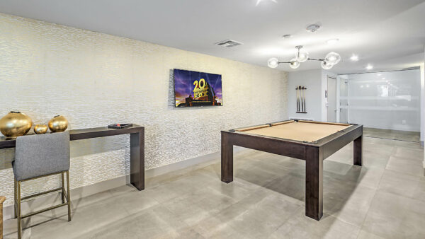 Game room with pool table, cue rack, table with decor, and TV.