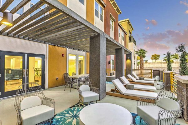 Rooftop patio with lounge chairs, dining table with chairs, and railing overlooking pool area.
