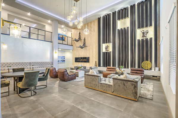 Clubroom with plush seating, dining table with chairs, glass light fixture, and mezzanine floor.