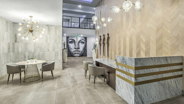 Lobby with stone tiles, desk with chairs, metal light fixtures, and artwork.